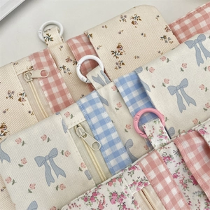 Detailed close-up of floral and plaid canvas coin purses with zipper and metal ring clips