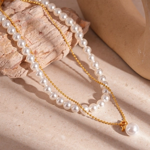 Macro view of double-layered gold pearl necklace set on natural stone and wood