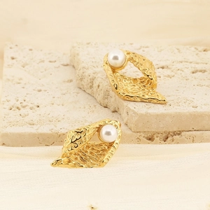 Vue macro de boucles d'oreilles géométriques dorées avec perles et texture martelée