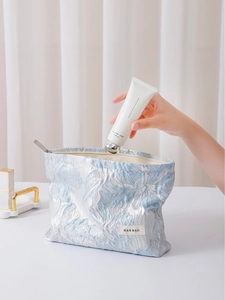 Light blue floral embossed makeup bag with silver embroidery and zipper closure