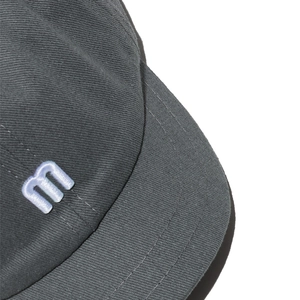 Gros plan détaillé d'une casquette gris foncé avec broderie 3D 'm' et bordure surpiquée