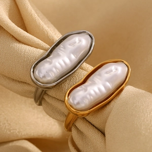 Macro shot of 18K gold and silver plated bar pearl rings on champagne silk background