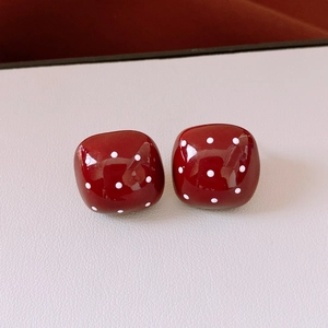 Detail view of red square resin earrings with white polka dots and high gloss finish