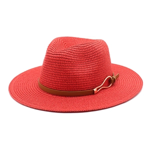 Detail of red straw fedora hat featuring wide brim and leather band with gold buckle