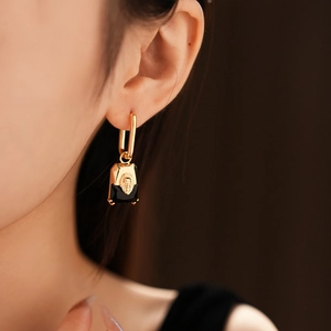 Macro detail of vintage gold-plated earrings with black rectangular lion head pendants