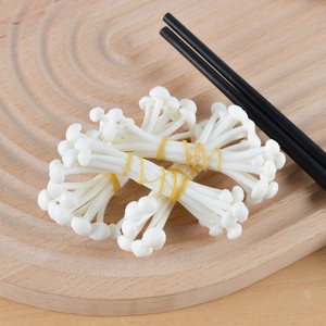 Realistic PVC enoki mushroom model with yellow ties on a wooden plate and black chopsticks