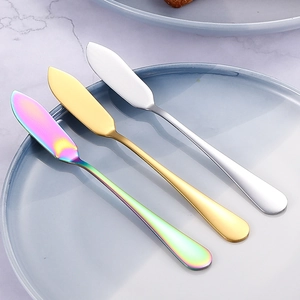 Trois couteaux à beurre en acier inoxydable or argent et arc-en-ciel sur une assiette