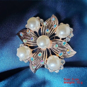 Detailed macro view of a golden camellia brooch featuring imitation pearls and crystals