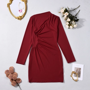 Detail of burgundy long sleeve fitted dress with ruched waist design on textured surface