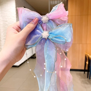 Close-up of gradient organza bow hair clip with pearl tassels and rhinestone flower
