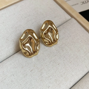 Detail of gold liquid metal earrings with irregular abstract design in a jewelry box