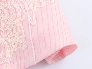 Nahaufnahme von rosa gestreiftem Stoff mit zarten weißen Blumenstickerei-Details