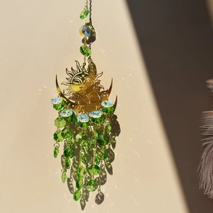 Close-up of golden sun and moon suncatcher with green faceted crystal beads decoration