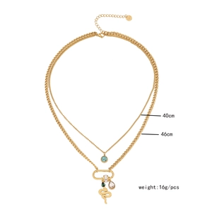 Close-up of double layer gold necklace with snake pendant and emerald green gemstones