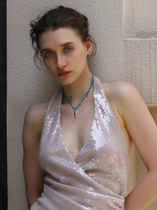 Detailed view of turquoise beaded necklace with gold leaf pendant on a model in sequins