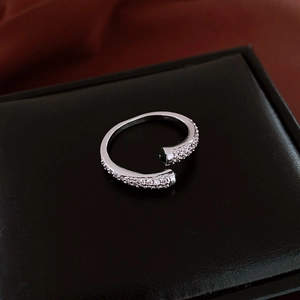 Gros plan sur une bague ajustable en argent avec zircon et pierre verte sur cuir noir