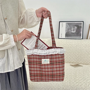 Detail of vintage brown plaid tote bag with intricate white lace trim and spacious interior
