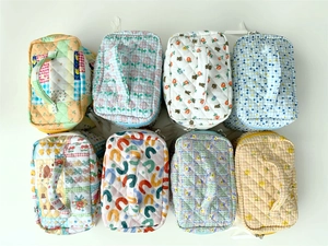 High-angle flat lay showing multiple quilted cosmetic bags with floral and plaid patterns