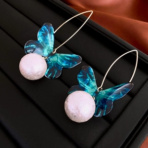 Detailed shot of teal acrylic butterfly earrings with pink textured faux pearl drops