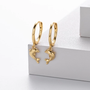 Close-up of gold dolphin pendant earrings on white geometric stands for modern jewelry display