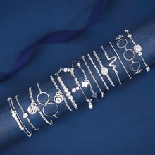Detail of silver multi-layer butterfly bracelets with lucky charm on a blue display