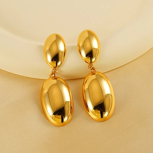 Detailed macro view of dual oval polished 18K gold titanium earrings on a luxury silk backdrop
