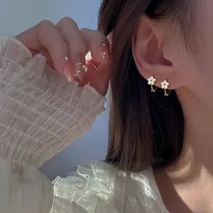 Elegant sterling silver gold-plated flower hoop earrings with white enamel on model