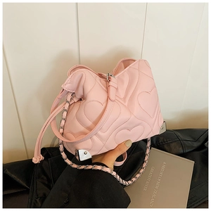 Detailed close-up of pink heart-quilted leather handbag with silver chain and metal corners