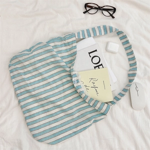 Detail of striped canvas tote bag showing button closure and large interior capacity