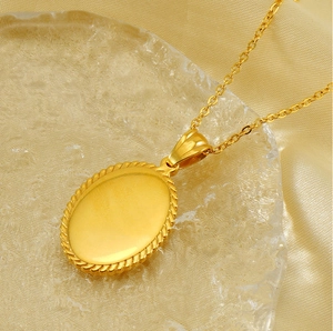 Macro shot of an oval gold-plated cross pendant with a textured rope border and fine O-chain