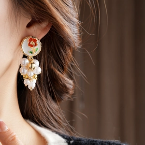 Détail de boucles d'oreilles fleurs vintage avec perles et pétales rouges sur oreille