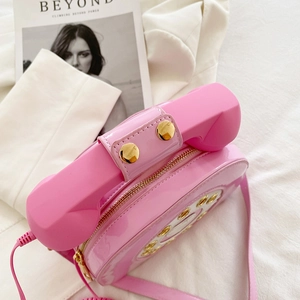 Macro detail of glossy pink patent leather telephone bag with golden button accents