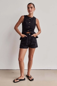 Dettaglio del gilet di jeans senza maniche e shorts a vita alta in nero lavato