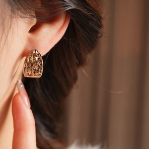 Gros plan de boucles d'oreilles dorées en U avec cristaux marron pavés sur un mannequin