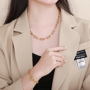 Detail of gold-tone chunky chain necklace and bracelet set worn with a stylish blazer