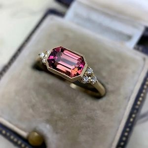 Vintage style gold ring featuring rectangular pink gemstone and accent side diamonds
