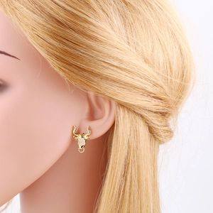 Close-up of golden bull head stud earrings with white zircons on a model's ear