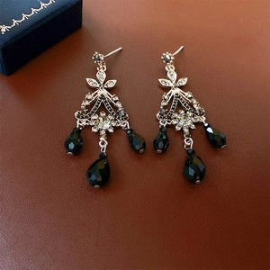 Detail of vintage silver earrings with black teardrop crystals on brown leather base