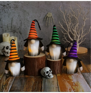 Close-up of lighted Halloween gnomes with colorful striped hats on rustic wooden surfaces