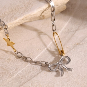 Detalle del collar bicolor con dije de estrella dorada, clip de papel y lazo de plata fina