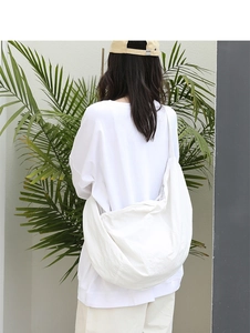 Borsa a tracolla in nylon bianco minimalista indossata in una scena di vita urbana