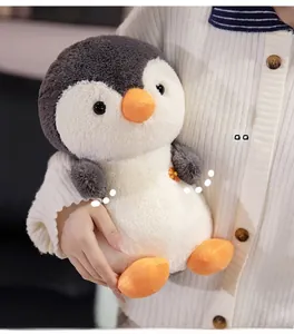 Detailed view of plush penguin doll with orange flower accent and soft texture
