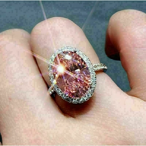 Elegant oval pink zircon ring with shimmering halo and silver band shown on finger