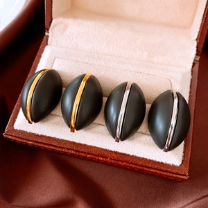 Macro shot of French retro oval wooden earrings with gold and silver stripe detailing