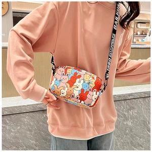 Detail of cartoon bunny crossbody bag featuring colorful patterns and wide branded strap