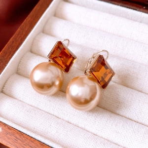 Détail macro de boucles d'oreilles vintage avec pierre ambre et perle de champagne