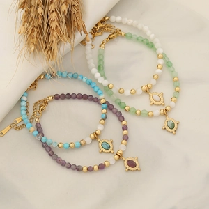Detailed shot of bohemian beaded bracelets with vintage metal charms on marble surface