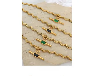 Detail of gold twisted rope necklaces with rectangular green and black gems on stone