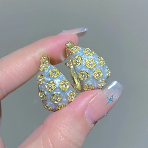 Macro shot of vintage teardrop earrings with blue enamel, gold flowers and zircon