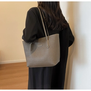 Chic grey-brown woven tote bag with shoulder straps shown on professional model